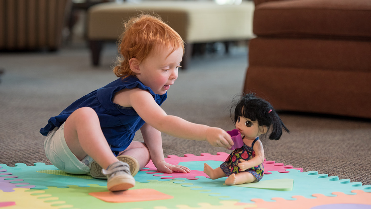child feeds baby doll a toy