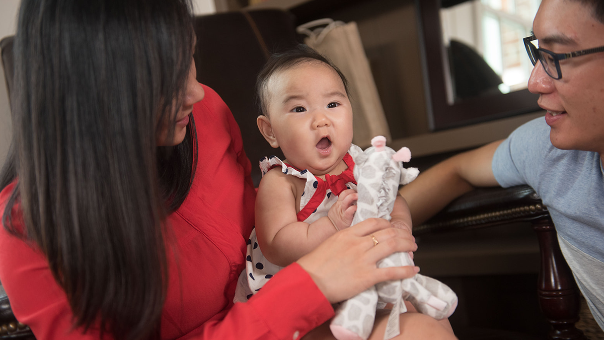 Baby holding toy with her parents