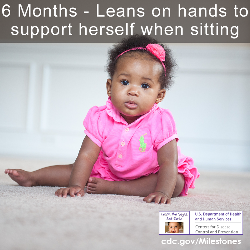 Baby girl sitting on the ground and is using her hands for support.