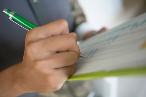 Writing on a checklist A person writing on a checklist.