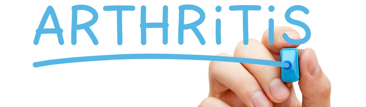 an adult hand writing the word arthritis