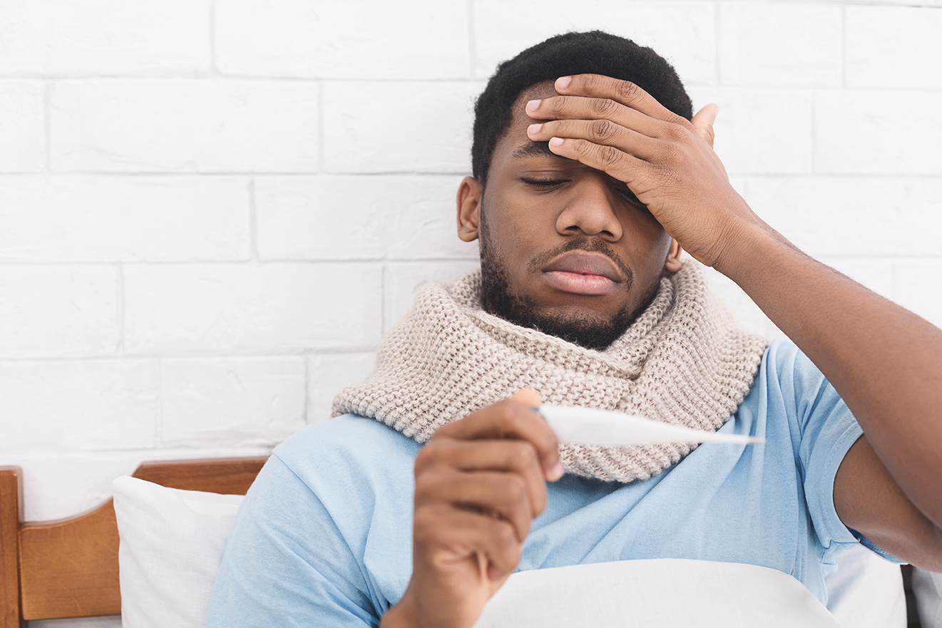 Hombre enfermo revisando un termómetro para ver si tiene fiebre