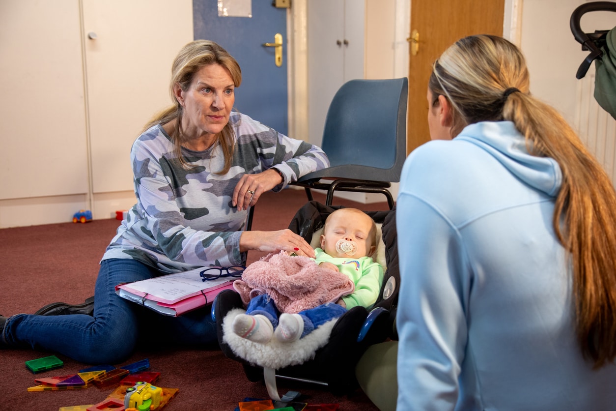 Child Care Worker with Young Adult A mother and baby child having a meeting with a childcare worker.