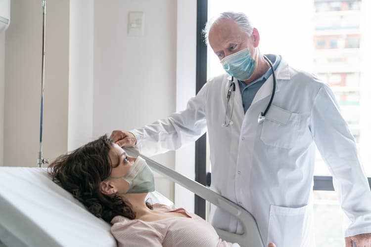 Photo of a breast cancer patient in a hospital bed talking to her doctor