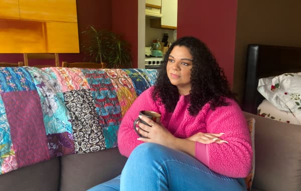 Charity laying on her couch holding a cup.