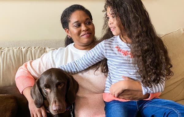 Jackie holding her daughter on her lap and her dog on her side.
