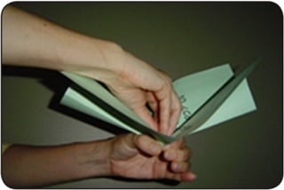 Figura 1 Una persona dobla hojas de papel verde para formar un repollo de papel