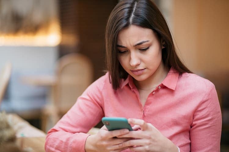 Foto de una mujer confundida mirando su celular