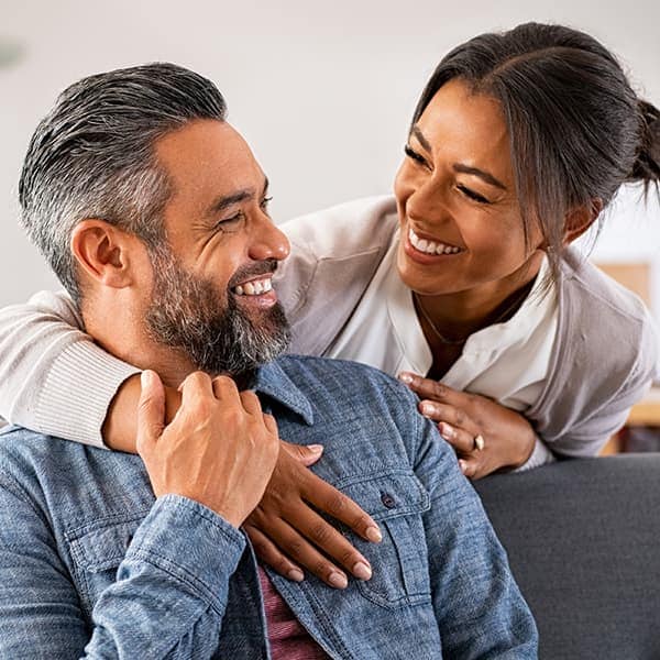 Two adults, a man, and a woman, embracing and smiling at one another.