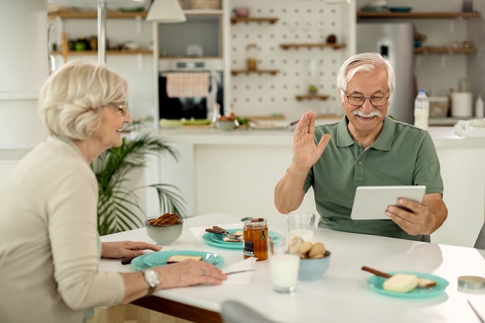 Photo of a mature man making a video call over a digital tablet at home