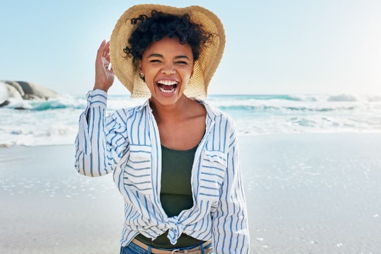 Photo of a woman on a beach wearing a hat and a long-sleeved shirt