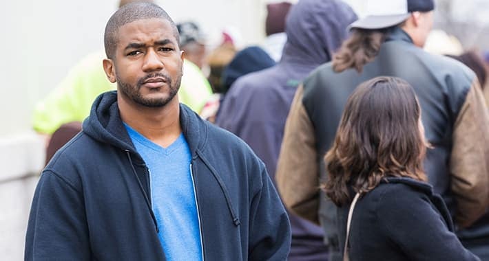 An African American man standing outside on a crowded city sidewalk