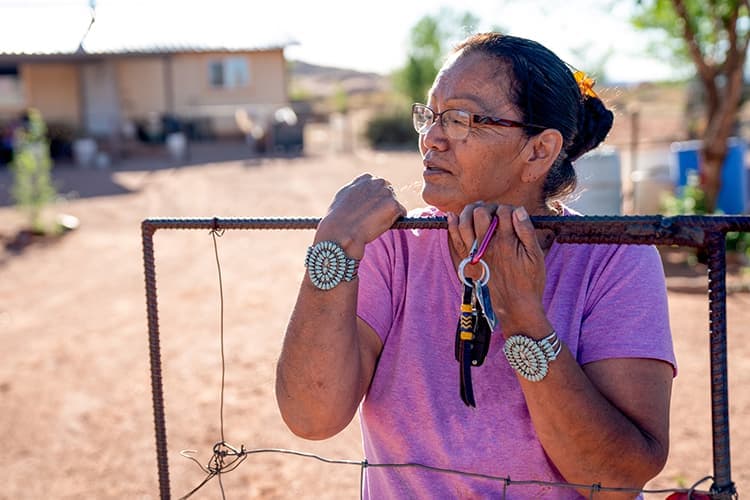 Mujer navajo de pie delante de la entrada de su casa en Monument Valley, Arizona.