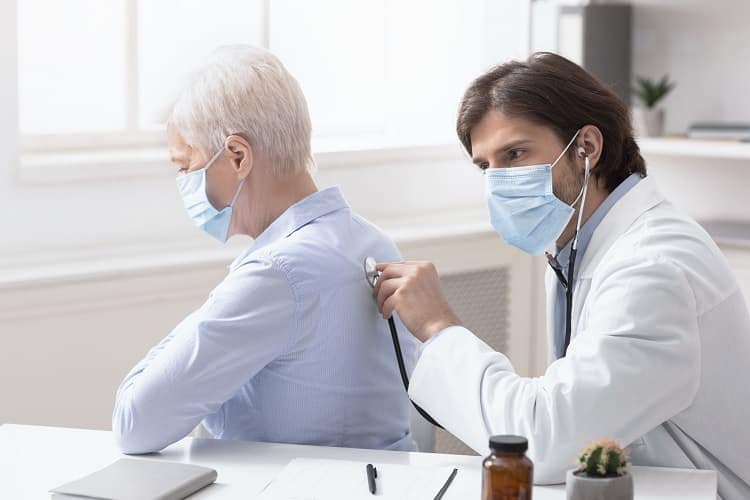 Foto de un doctor escuchando los pulmones de un hombre con un estetoscopio