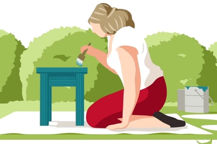 Imagen de una mujer en su patio pintando su mesa.