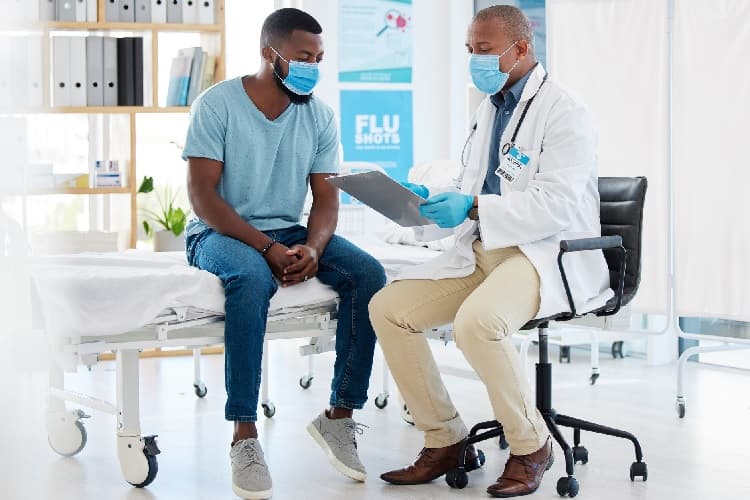 Photo of a doctor with his digital tablet talking to his patient about treatment