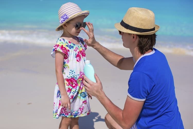 Photo of a father putting sunscreen on his young daughter