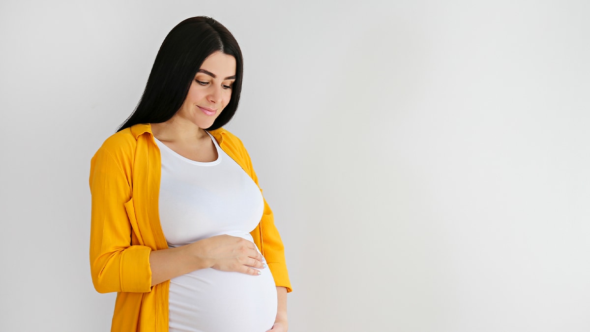 Pregnant woman with yellow shirt holding belly Pregnant woman with yellow shirt holding belly