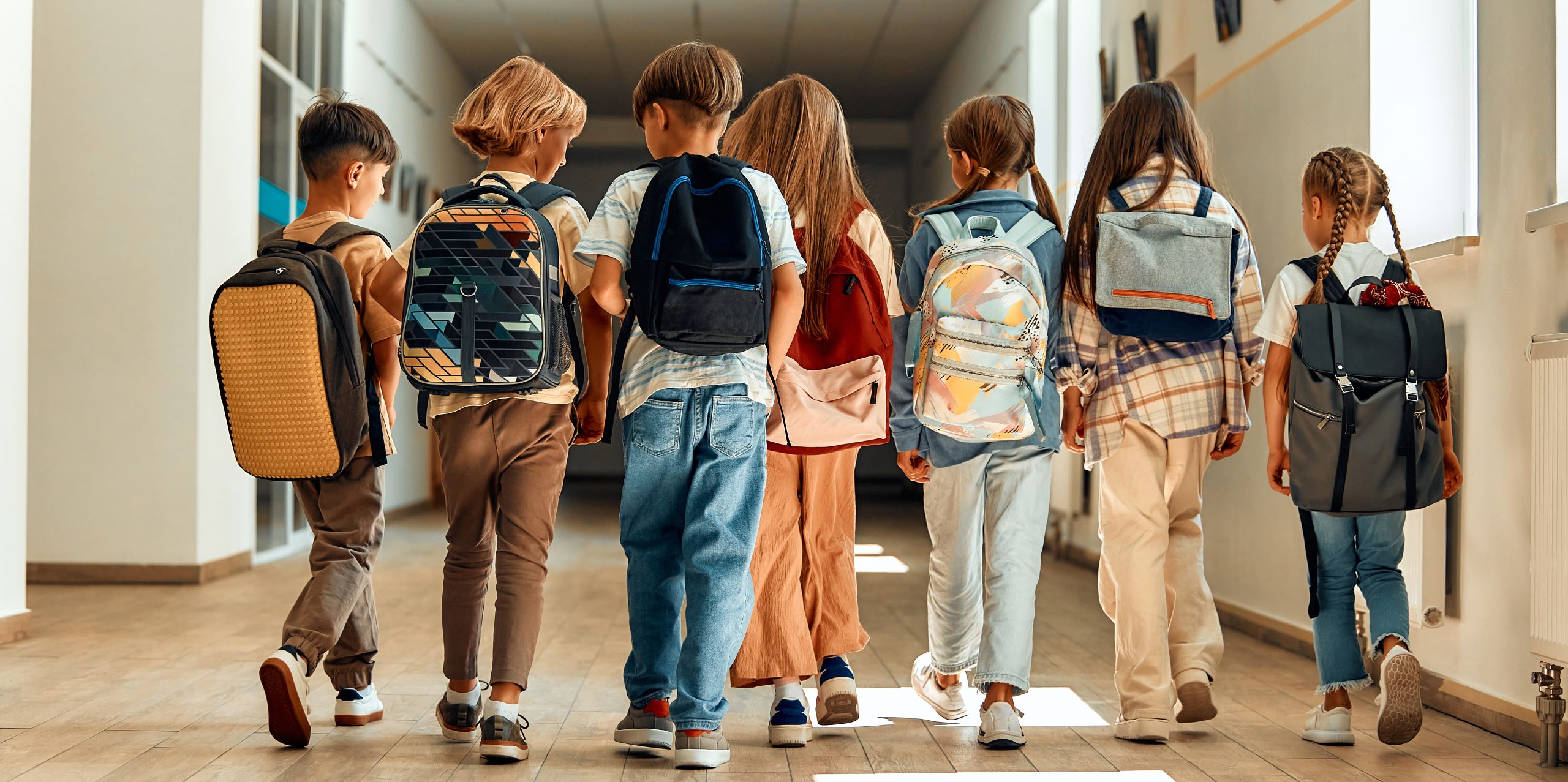 Children in a school hallway with backpacks