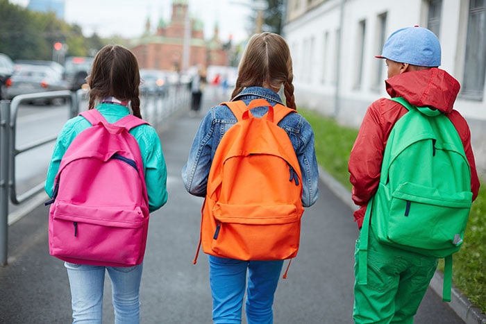 Going to school Tres chicas con mochilas caminando a la escuela.