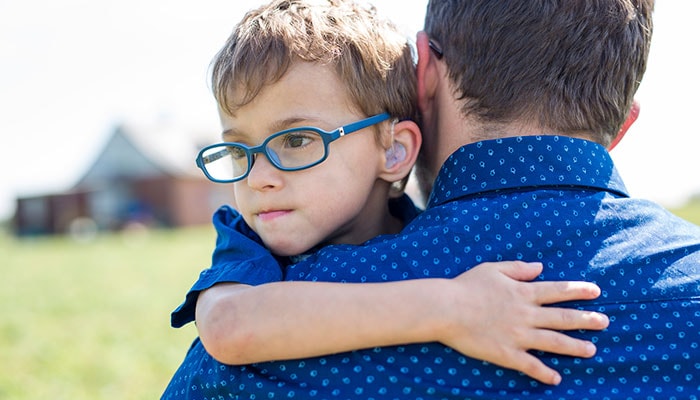boy-hugging-father A boy with a hearing aid, hugging his father.