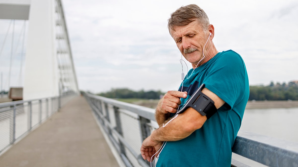 Senior runners in nature, tying shoelaces. Man with smartphone.