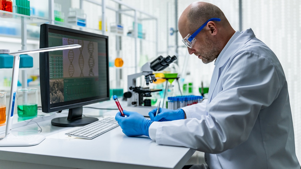 researcher A male scientist in a white lab coat examines a blood sample at a laboratory