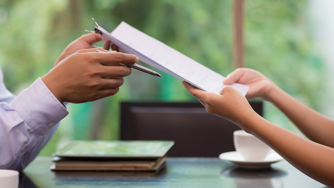 CDC Contracts feature A worker hands a contract to a co-worker.