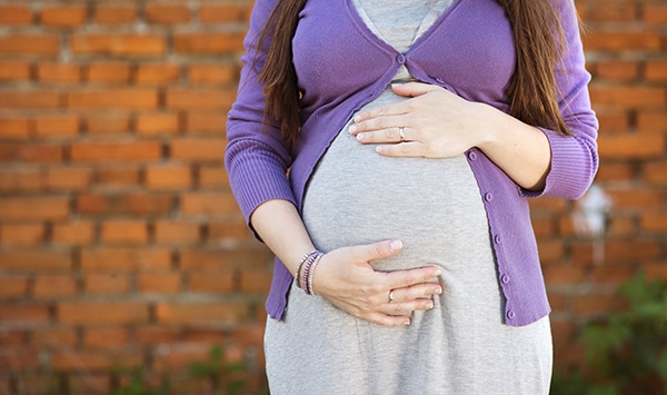 — title missing — Pregnant mother holding belly.