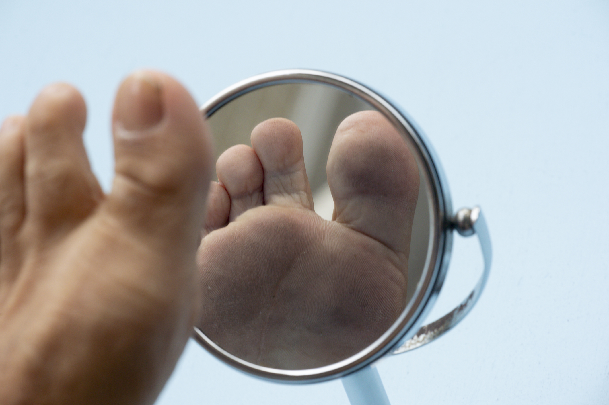 Feet in mirror low section of man by mirror against blue background