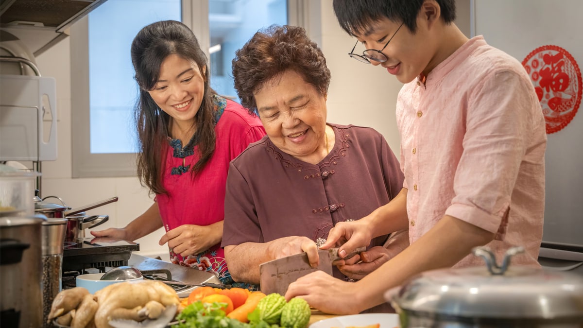 Hombre asiático joven aprendiendo de su madre y abuela a preparar alimentos. Hombre asiático joven aprendiendo de su madre y abuela a preparar alimentos.
