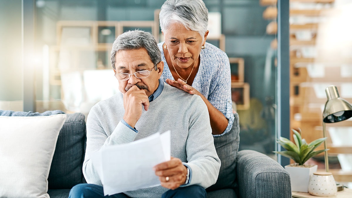 There can be burdens to budgeting mature couple looking worried while going through paperwork together at home