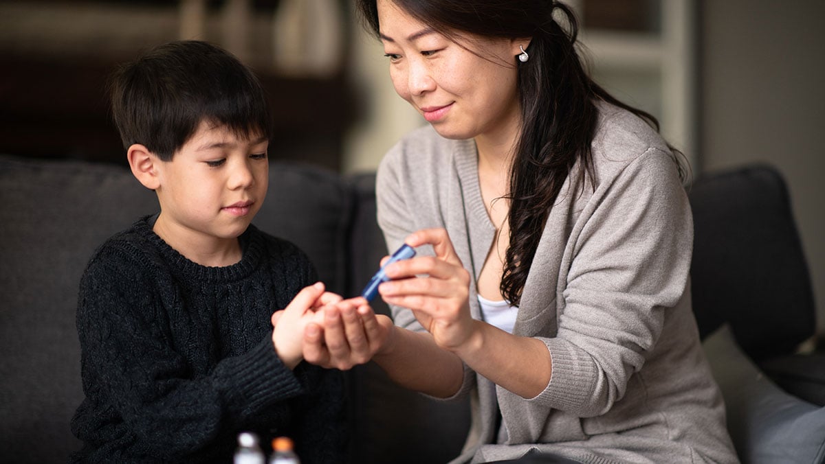 Mother helping son check blood sugar levels mother helping son check blood sugar levels