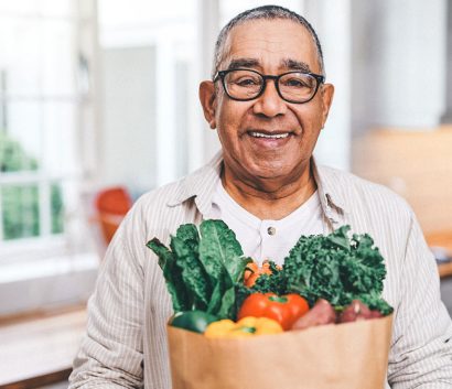 Shot of a elderly man holding a grocery bag in the kitchen Shot of a elderly man holding a grocery bag in the kitchen