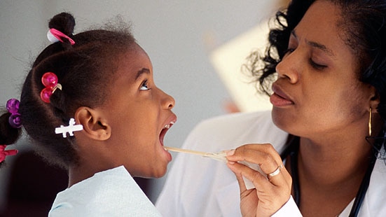 Doctor young girl Imagen de una médica examinándole la garganta a una niña pequeña con un depresor de lengua.
