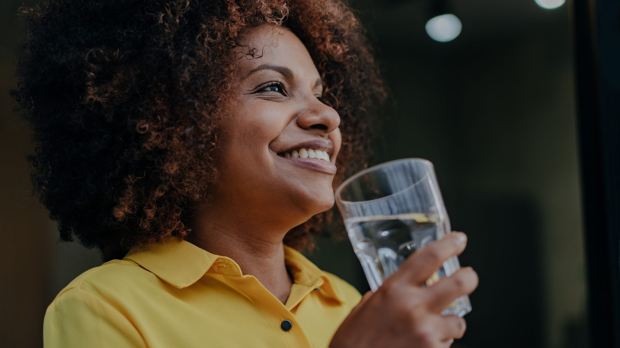Woman drinking water from a glass Smiling person holding a glass of water