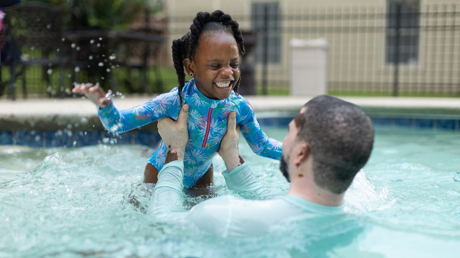 DP223PoolPlayBlackGirlDad.jpg Black father and daughter play in swimming pool.