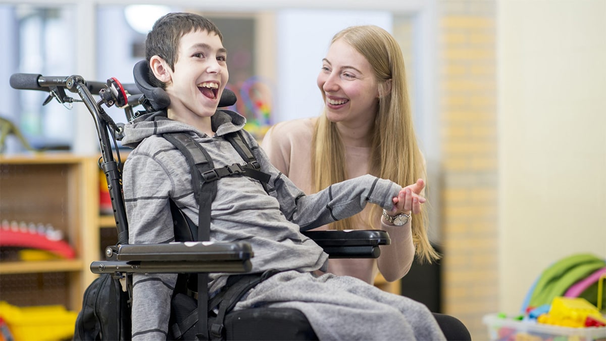 Caregiver sitting alongside student Caregiver sitting alongside student with a mobility disability.