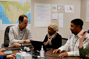 Two men and a woman sitting at table conversing