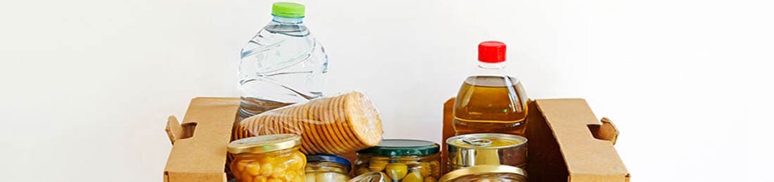  Una caja con alimentos enlatados, alimentos en frascos y líquidos embotellados.