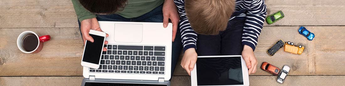 Un padre y un hijo juntos con varios dispositivos de medios a su alrededor.