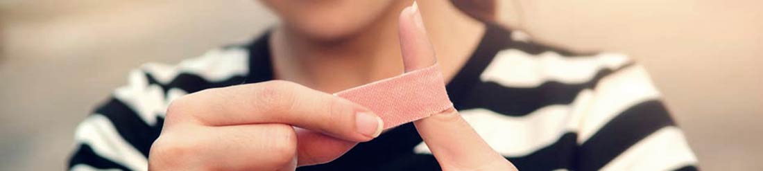 Una foto de una mujer joven poniéndose una venda adhesiva en el dedo. Una foto de una mujer joven poniéndose una venda adhesiva en el dedo.