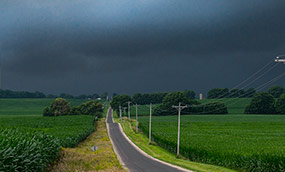 Las nubes oscuras se ciernen sobre los campos y un camino rural Las nubes oscuras se ciernen sobre los campos y un camino rural