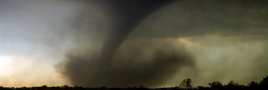 Un gran tornado abre un camino a través de un bosque y arroja escombros al aire. Un gran tornado abre un camino a través de un bosque y arroja escombros al aire.