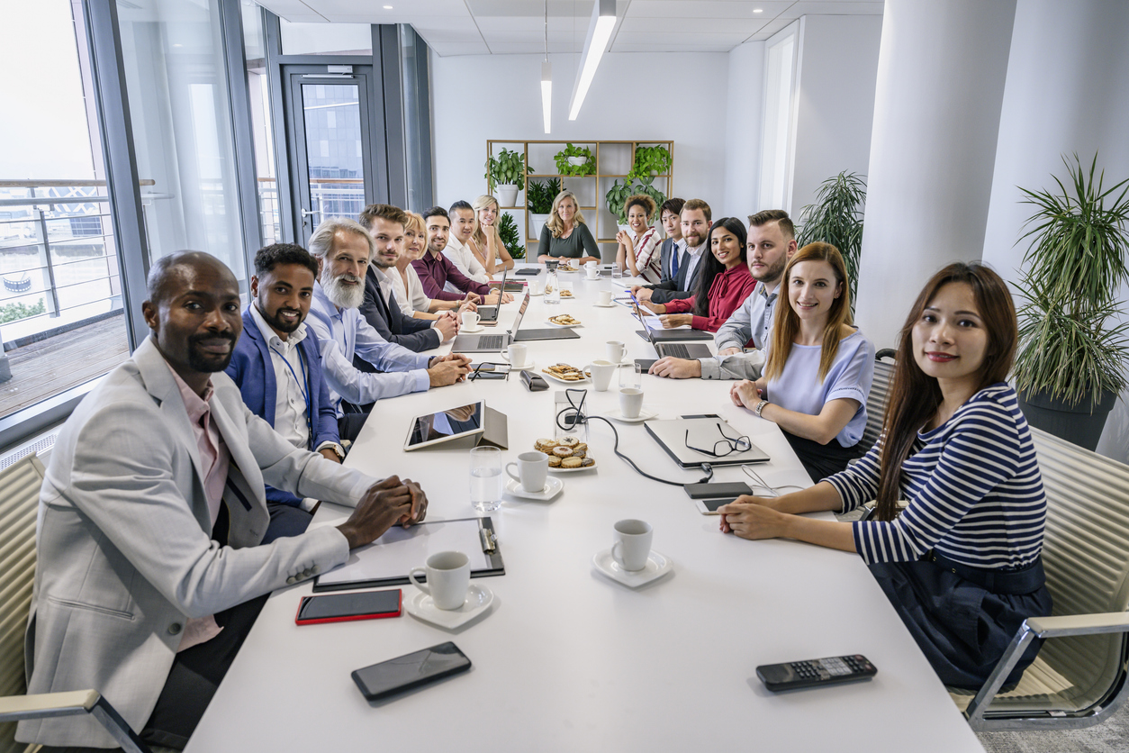 Food service guidelines team happily meeting around conference table in office.