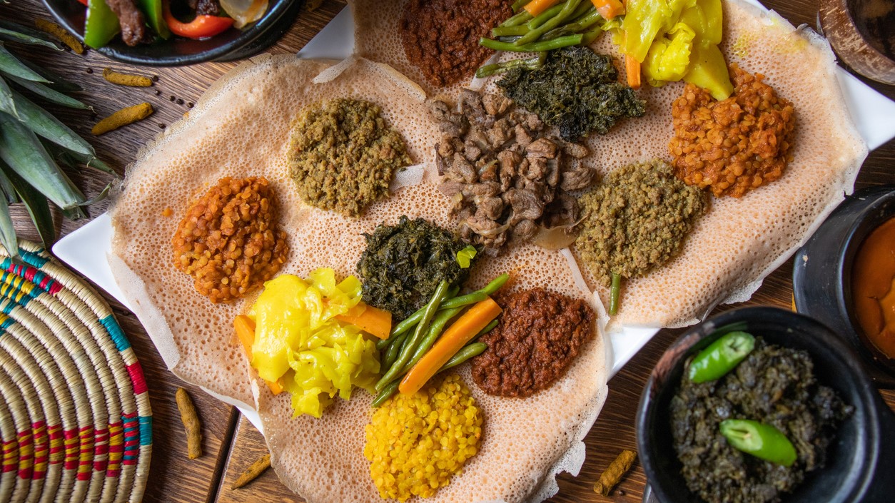 A sample of Ethiopian lentils, vegetables, and other foods on a bed of teff.