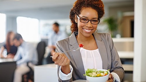 Woman eating salad in cafeteria.