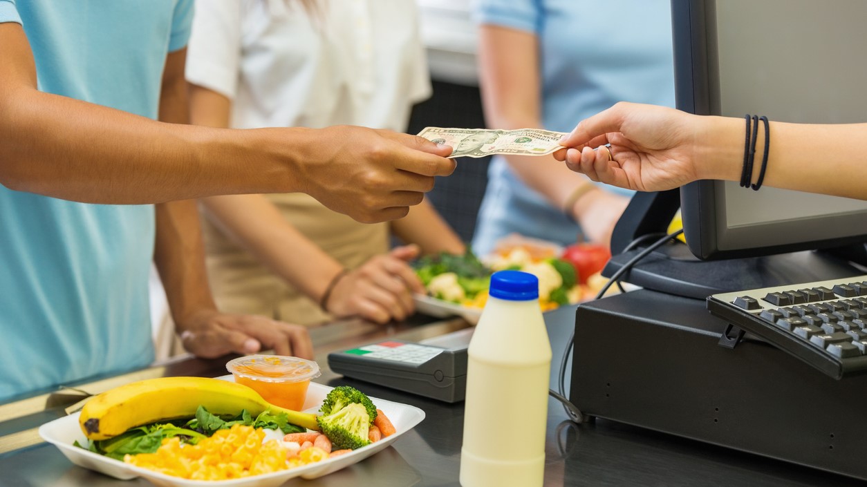 Person paying for meal with cash in a cafeteria.