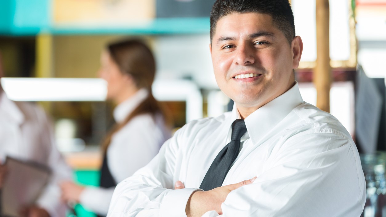 Food service vendor standing with arms folded and smiling at camera.