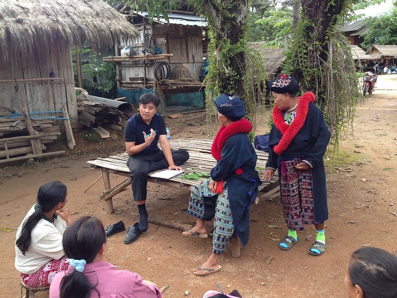 Principle image A male health professional speaking with community members outside in rural Thailand.